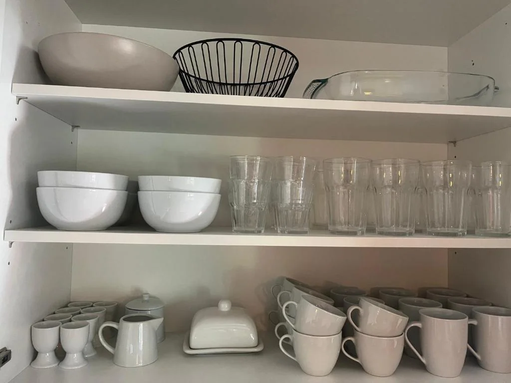 Geöffneter Geschirrschrank mit Tassen, Trinkgläsern und Schüsseln